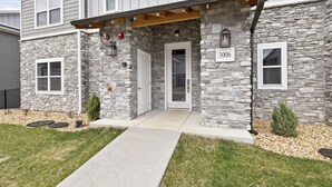 A two-story house with a stone facade, a covered porch, and a front door.