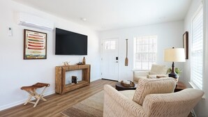 A living room with a fireplace, a television mounted on the wall, and a comfortable seating area with a sofa and armchairs.