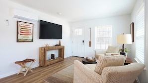 Ein Wohnzimmer mit Kamin, einem an der Wand montierten Fernseher und einer gemütlichen Sitzecke mit einer Couch und Sesseln.