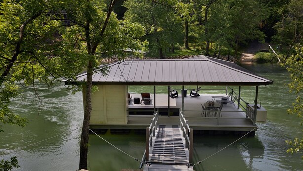 Een drijvend huis met een steiger, terras en uitzicht op het water.