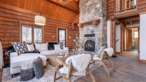 A log cabin interior with a stone fireplace, wooden furniture, and a cozy fireplace area.