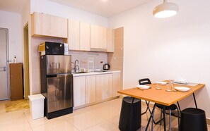 Enjoy meals and social gatherings in this kitchen and dining area, featuring a stainless steel refrigerator, sink, and microwave, as well as a dining table with four chairs.