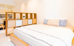 Relax in a serene bedroom with a large bed, wooden headboard, and a small desk for work.