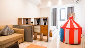 Ein modernes Hotelzimmer mit einer Couch, einem Holzschrank mit Dekoration, einem Bett und einer roten und weißen Streifenkonstruktion wie ein Zelt.