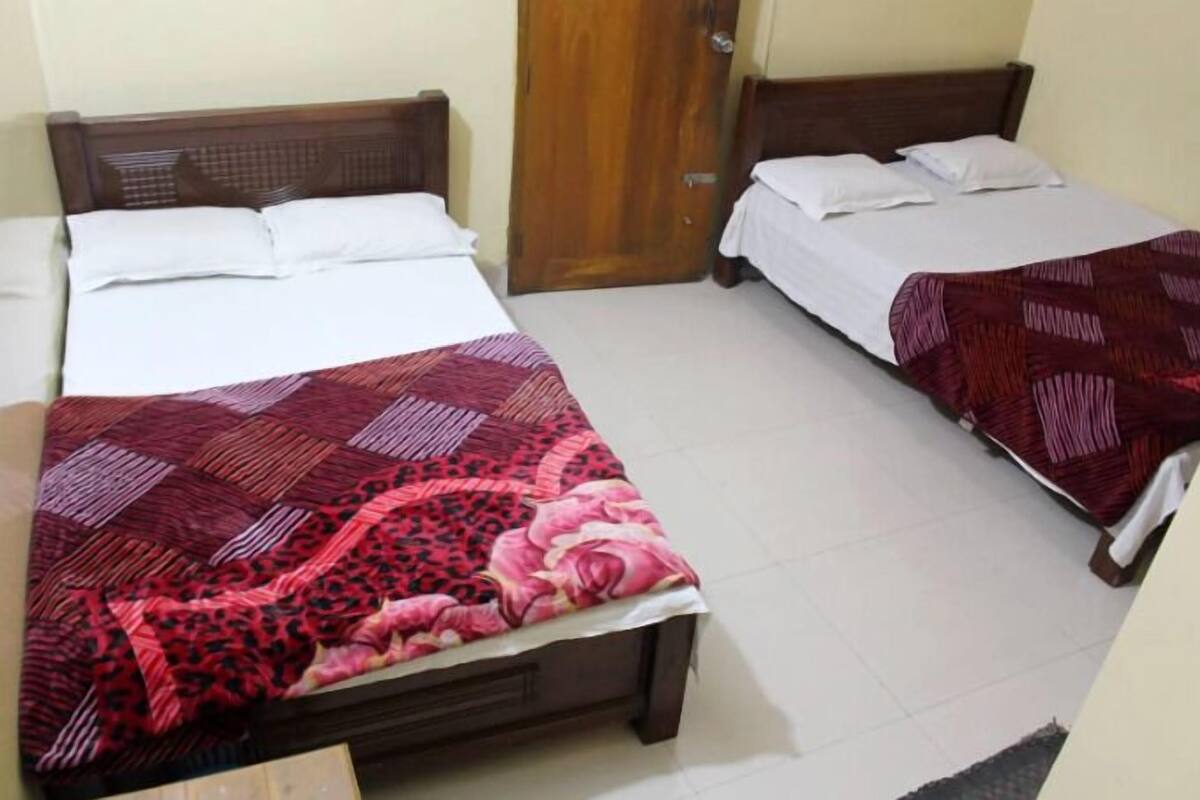 Two single beds with wooden headboards and white bedding, one with a red and pink patterned bedspread and the other with a red and white patterned bedspread.