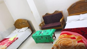 Una habitación con dos camas individuales, una mesa verde y una silla de madera.