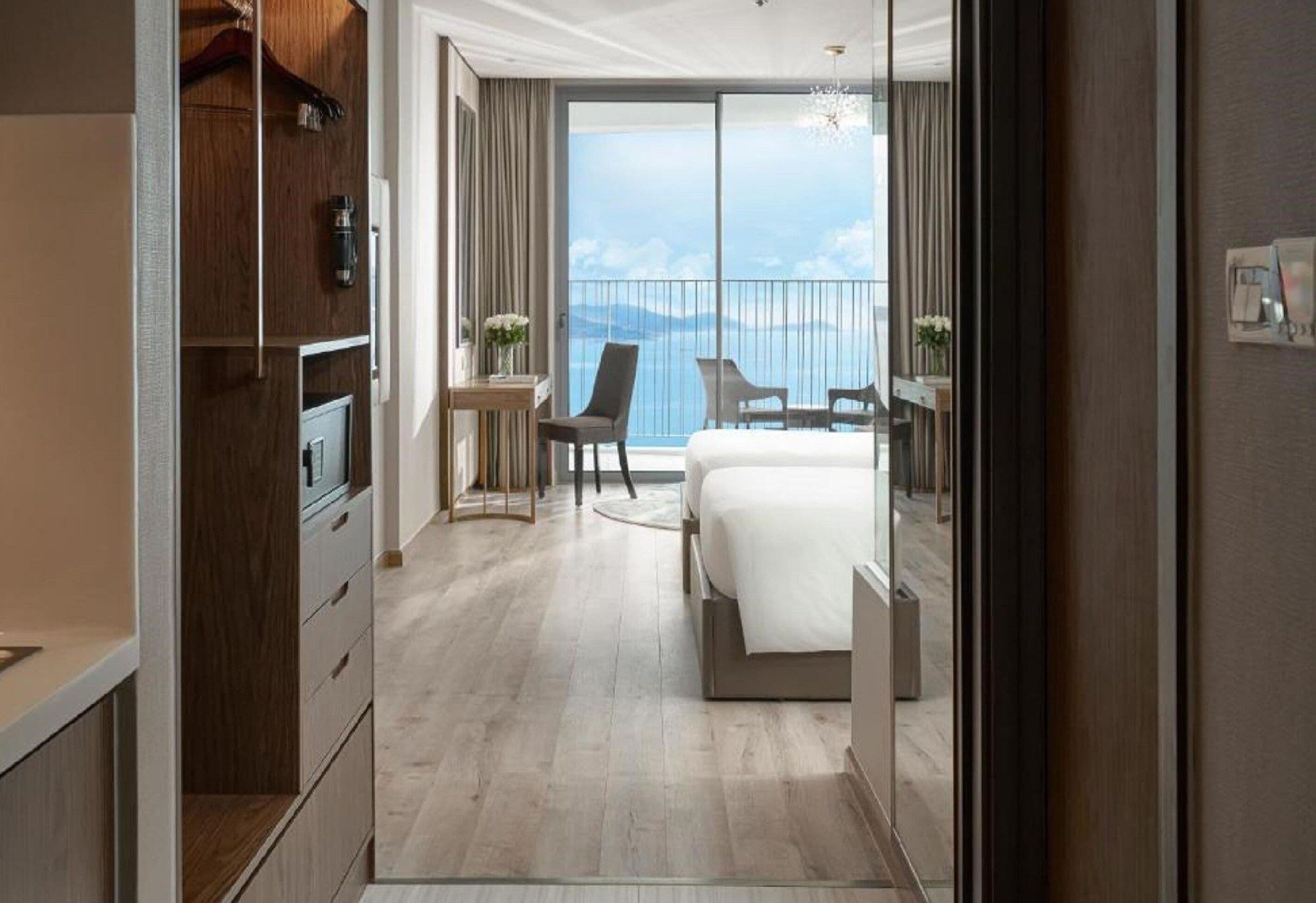 Une chambre d’hôtel moderne avec un grand lit, un bureau et une vue sur la mer.