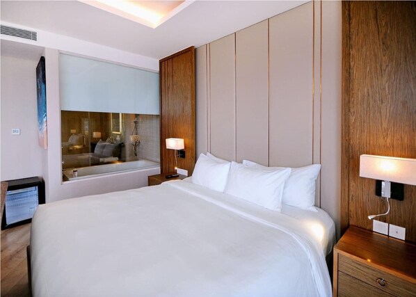 A hotel room with a large bed, a wooden headboard, a mirror, and two bedside lamps.