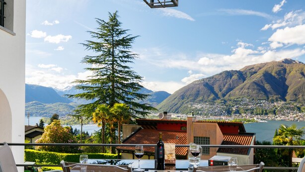 A terrace with a table and chairs, overlooking a mountainous landscape and a lake. - Residenza Miralago Apt. D32 by Interhome (Piazzogna)