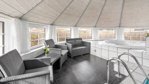 A modern spa area with wicker furniture, a large bathtub, and a view of the outdoors.