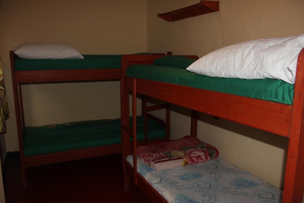 A bunk bed room with two levels, each with a green mattress and white pillows.