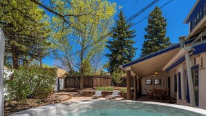 Un jardin avec un jacuzzi, des chaises longues, une table à manger et une clôture en bois.