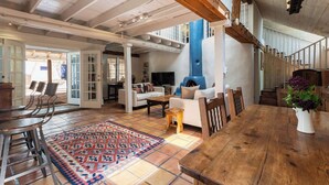 Un vaste espace de vie doté d’un haut plafond, de poutres en bois, d’un grand tapis et d’une cheminée.