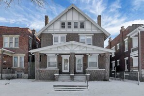 A two-story building with a symmetrical facade, a central entrance with steps, and a brick exterior.
