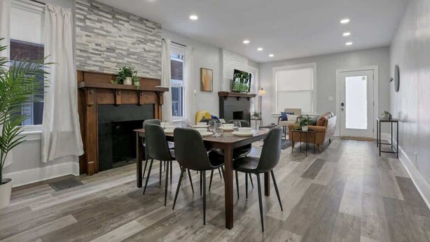 A modern living room with a fireplace, dining area, and a sofa.