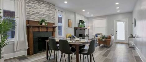 A modern living room with a fireplace, dining area, and a sofa.