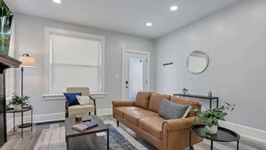 A living room with a brown leather sofa, a small coffee table, a side table, a lamp, and a potted plant.