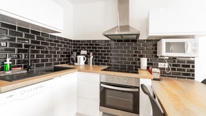 Una cocina moderna con salpicadero de baldosas blanco y negro, electrodomésticos de acero inoxidable y encimera de madera.