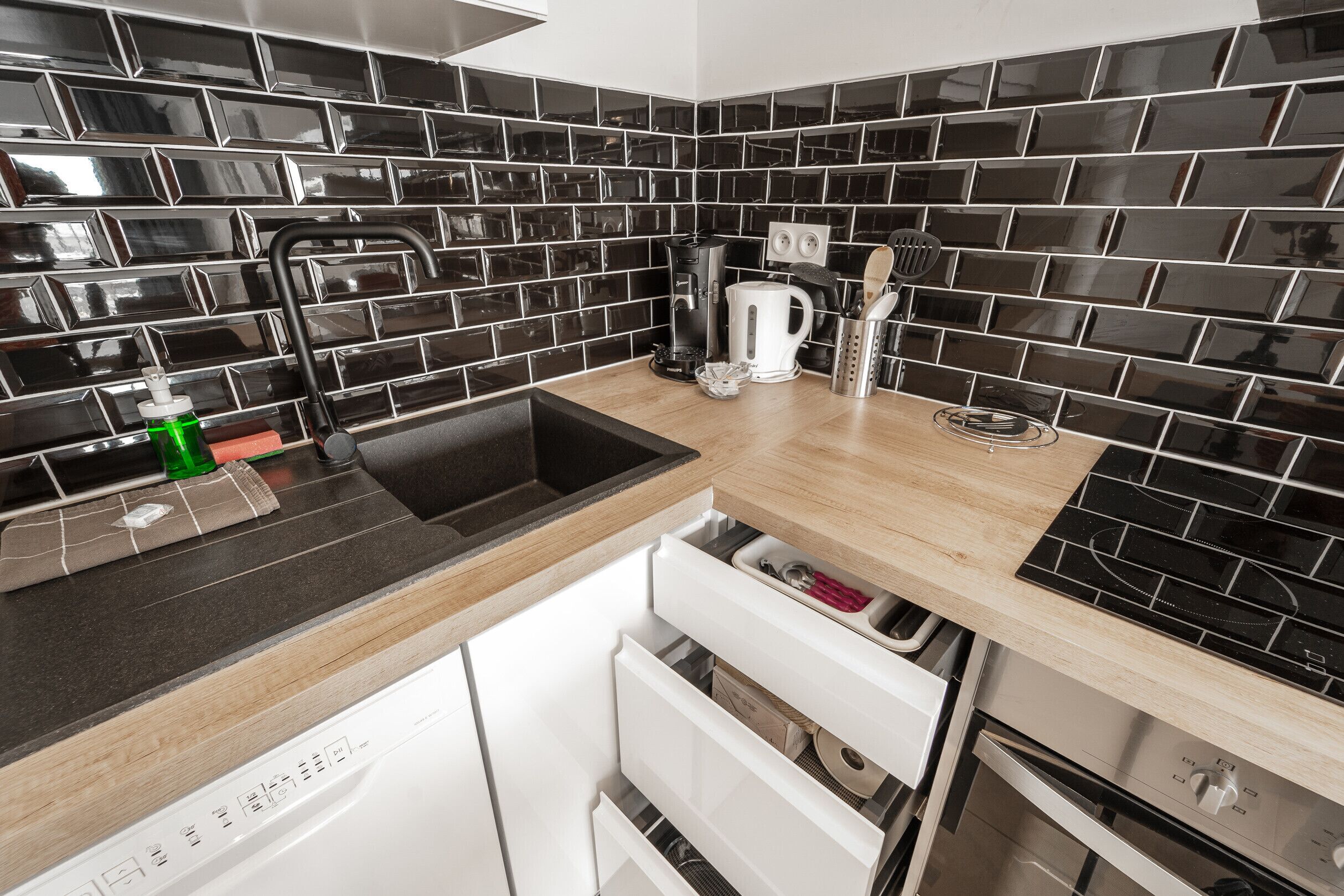 Eine moderne Küche mit schwarzem Fliesenrückwand, Edelstahlgeräten und einer Holz Arbeitsplatte.