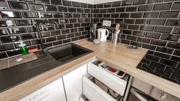 Eine moderne Küche mit schwarzem Fliesenrückwand, Edelstahlgeräten und einer Holz Arbeitsplatte.