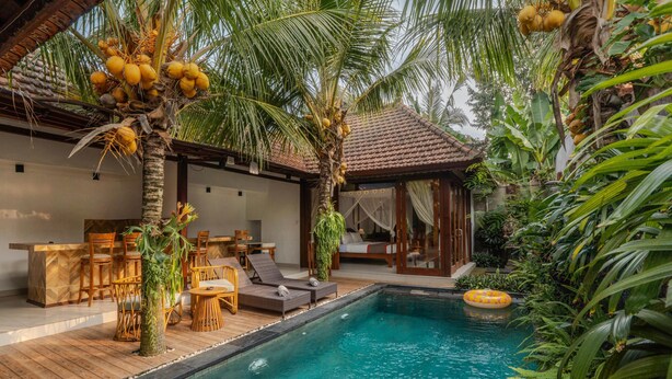 A pool area with lounge chairs, a wooden deck, and a covered seating area with a view of the pool. - The Jema Villa Ubud (Ubud)