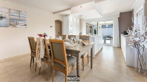 Un coin repas avec une table en bois, dressée pour quatre personnes, entourée de chaises.