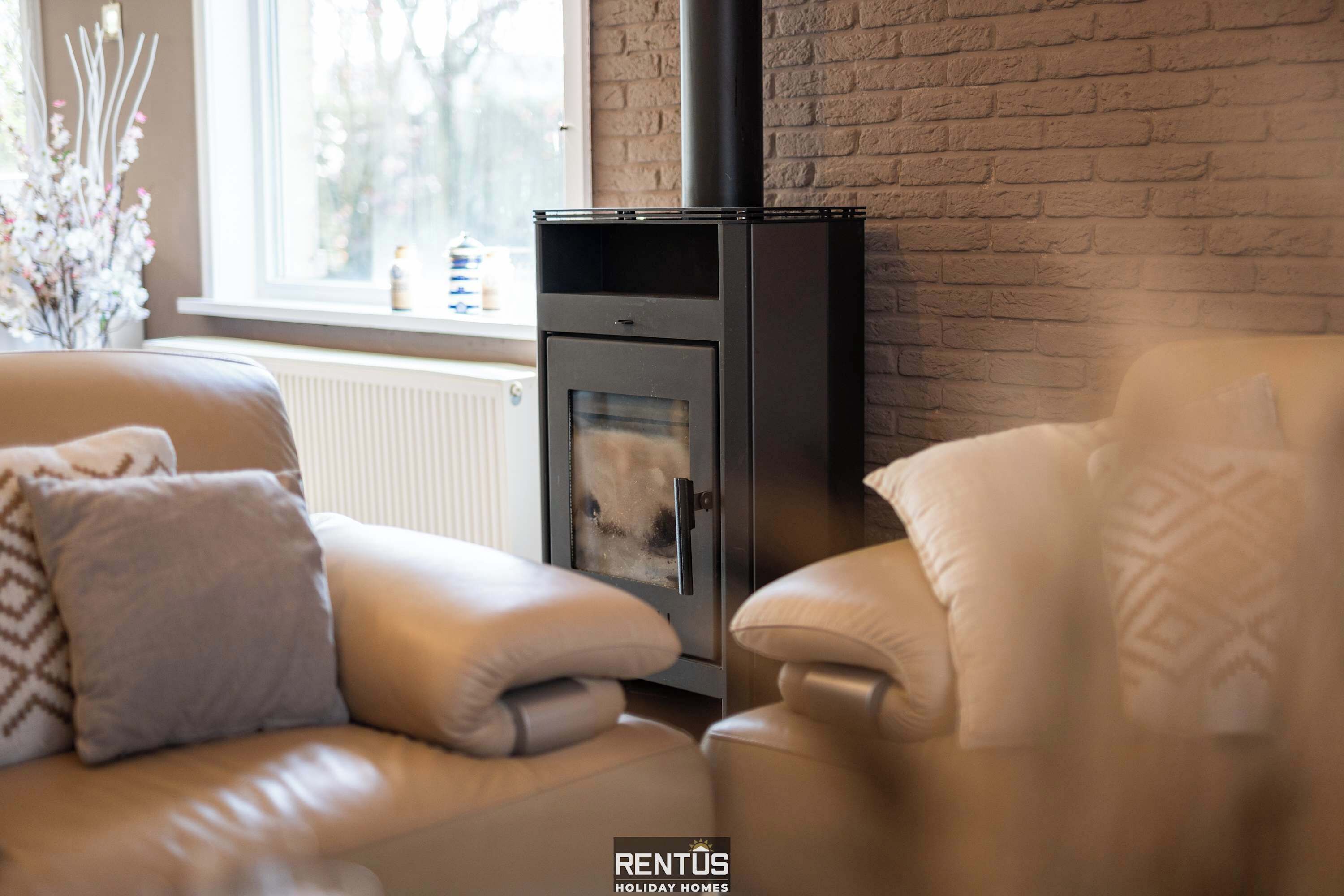 A cozy living room with a modern fireplace, a comfortable sofa, and a window with a view.