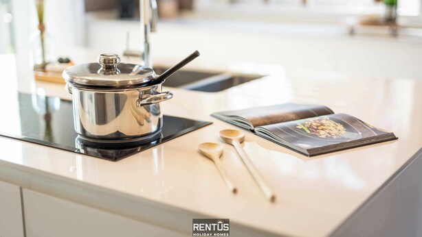 Un plan de travail de cuisine avec une casserole en acier inoxydable, des cuillères en bois et un magazine.