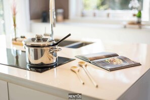 A kitchen counter with a stainless steel pot, wooden spoons, and a magazine. - Villa T’Uzetje – villa with pool in Oostduinkerke (Oostduinkerke)