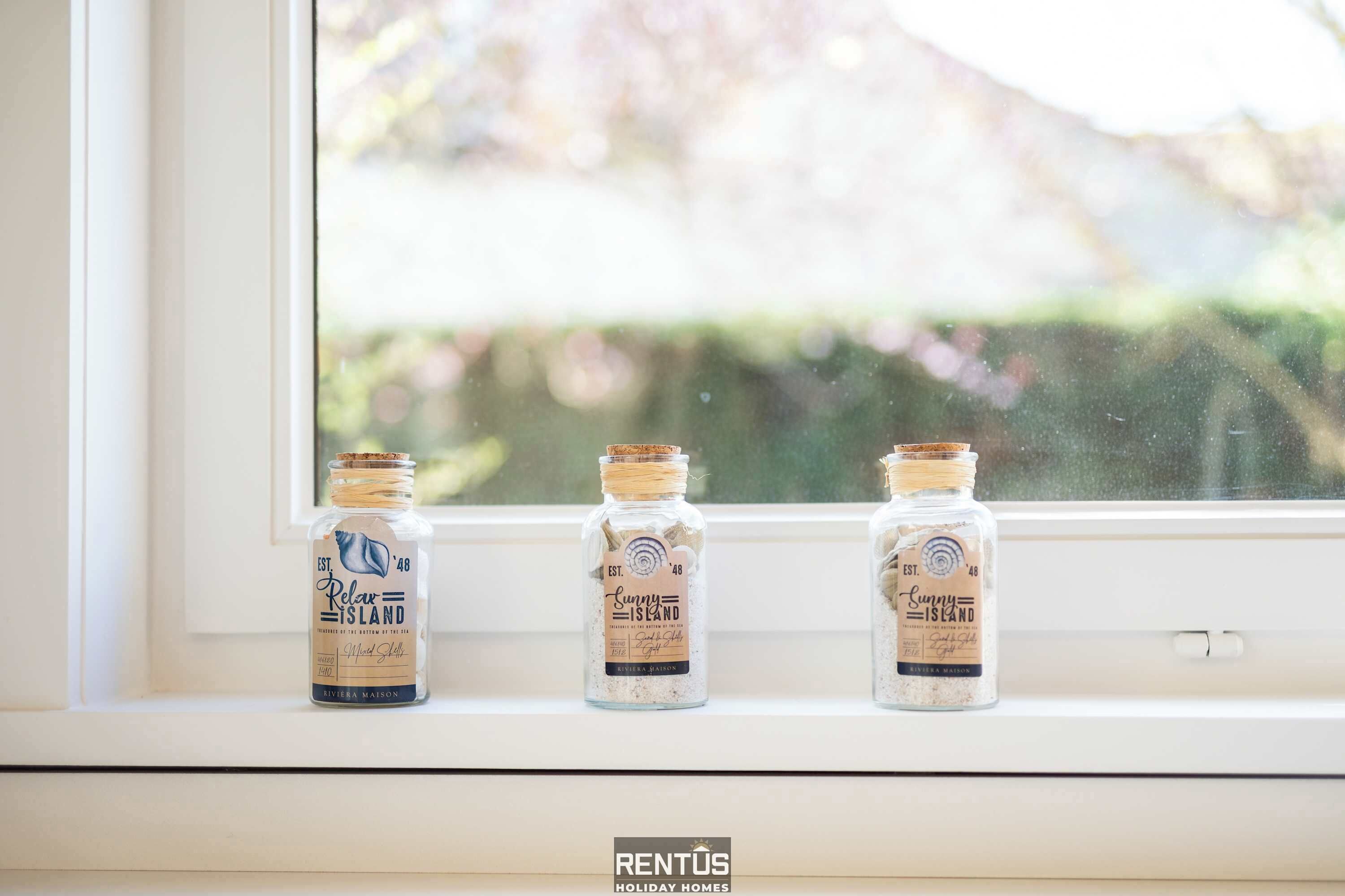 Three glass bottles with cork stoppers labeled 'Relax Island' on a windowsill.