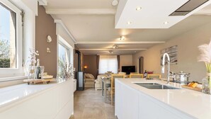 Une cuisine moderne avec un îlot central, un coin repas avec un canapé et un téléviseur en arrière-plan.