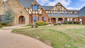 A large, two-story stone building with a symmetrical facade, multiple windows, and a well-maintained lawn. - Spacious Edmond Vacation Rental w/ Shared Pool! (Edmond)
