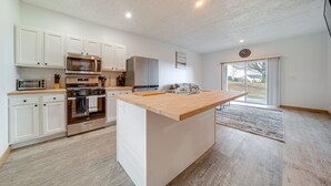 A modern kitchen with white cabinetry, stainless steel appliances, and a wooden island. - 4 Mi to Lake: Golf-View Erie Condo w/ Porch (Erie)
