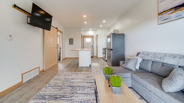 A modern living room with a grey sofa, a coffee table, and a flat-screen TV mounted on the wall. - 4 Mi to Lake: Golf-View Erie Condo w/ Porch (Erie)