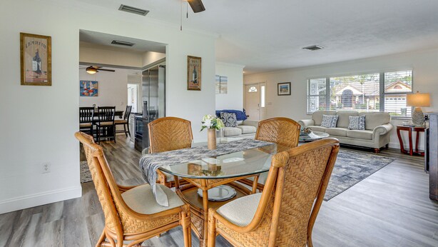 A dining area with a glass-top table, wicker chairs, and a ceiling fan.