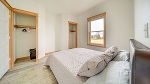 Un dormitorio con una cama grande, un vestidor y una ventana que ofrece vistas al exterior.