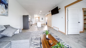 Un salon moderne avec un canapé gris, une table basse en bois et un tapis à motifs bleus.