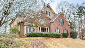 A two-story house with a brick exterior, a front porch, and a well-maintained lawn. - Modern Stone Mountain Home w/ Spacious Deck, Grill (Stone Mountain)