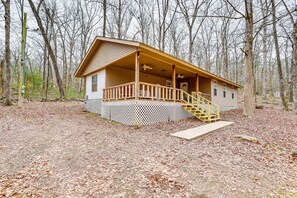 Une cabane dotée d’une terrasse en bois, d’un escalier et d’un porche grillagé.