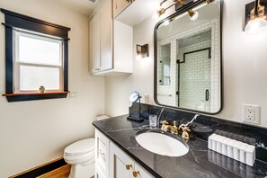 A bathroom with a white toilet, a black marble sink, and a large mirror. - Walkable Dallas Bungalow: 4 Mi to Downtown (Dallas)
