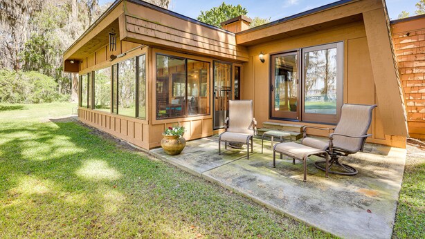 A modern house with large windows, a patio with outdoor furniture, and a well-maintained lawn. - Unique Melrose Home w/ Private Dock & Lake Access! (Melrose)