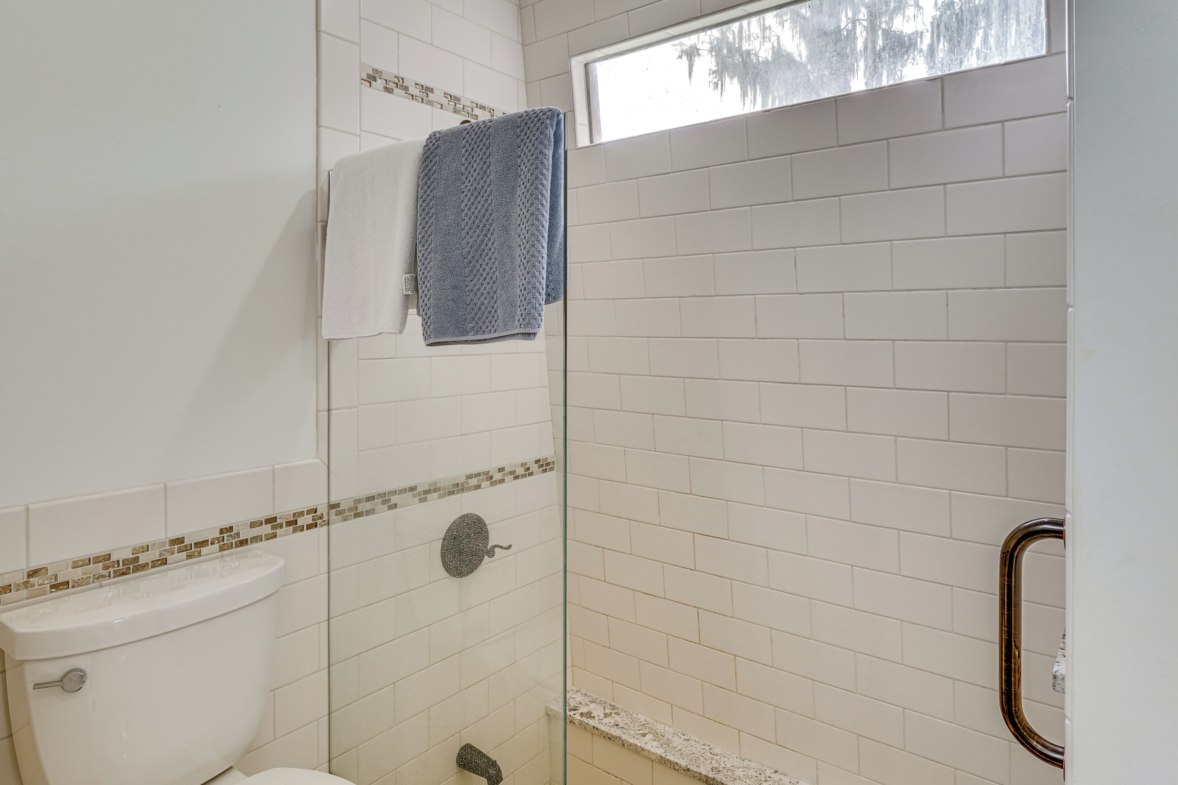 Une salle de bain comprenant des toilettes, une douche avec une porte en verre et un porte-serviettes.