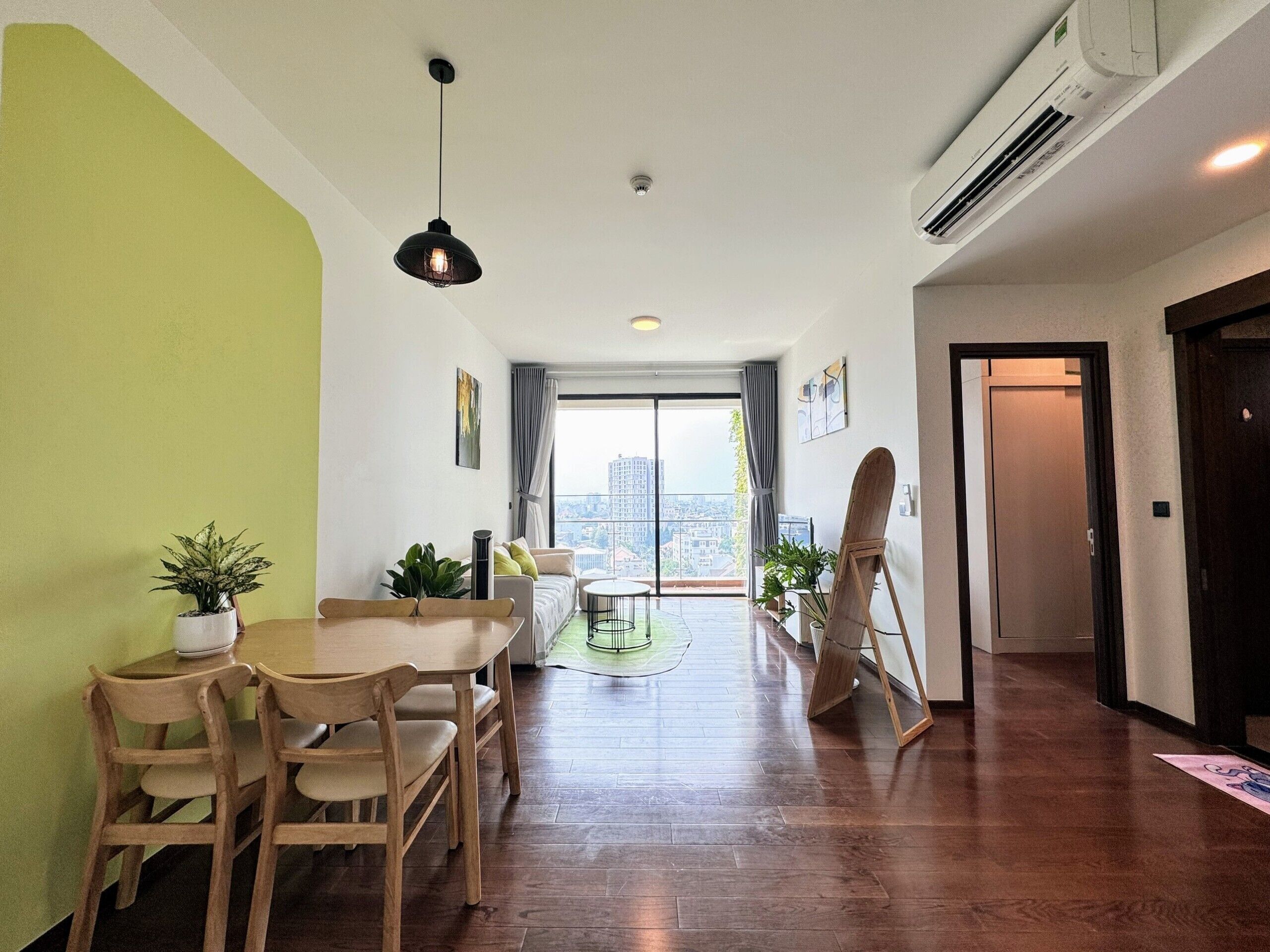 A modern living room with a dining area, large windows, and a view of the city.
