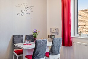 A dining area with a white table, red cushions, and a decorative wall with text.