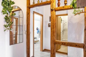 A hallway with a wooden door frame, a mirror, and a hanging plant.