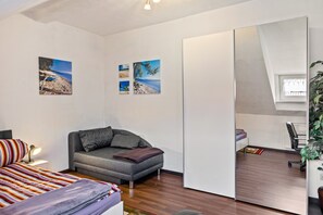 A modern bedroom with a bed, a sofa, a desk, and a large mirror.