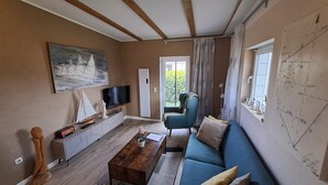 Un salon avec un téléviseur, un canapé, une table basse et un tableau au mur.