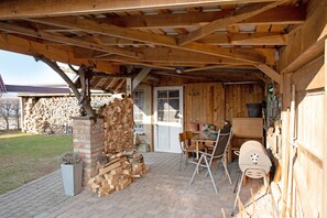 Un espace extérieur abrité, doté d’une cheminée en briques, d’une table avec des chaises et d’un barbecue.