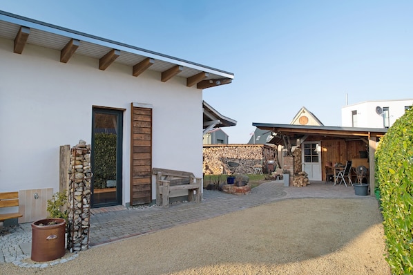 A building with a stone wall, wooden bench, and a gravel driveway.