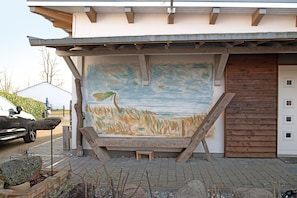 A building with a mural, a wooden door, and a car parked outside.
